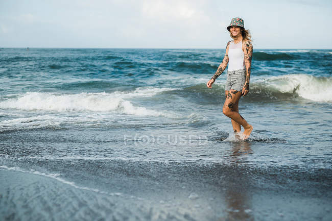 Mujer sonriente caminando en la playa - foto de stock