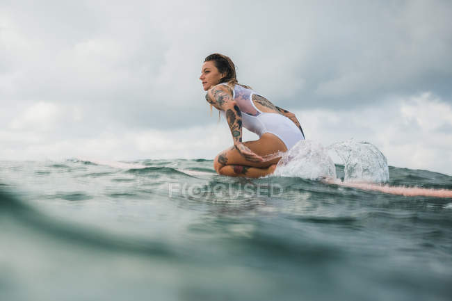 Жінка сидить на дошці для серфінгу — стокове фото