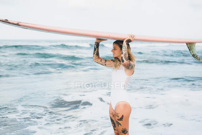 Donna che tiene tavola da surf sulla spiaggia — Foto stock
