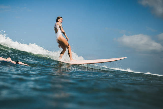Femelle surfeur attraper vague — Photo de stock
