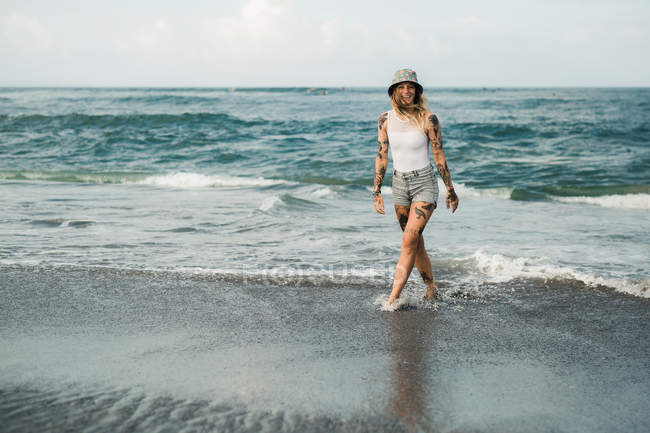 Femme souriante marchant sur la plage — Photo de stock