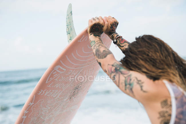Donna che tiene tavola da surf sulla spiaggia — Foto stock
