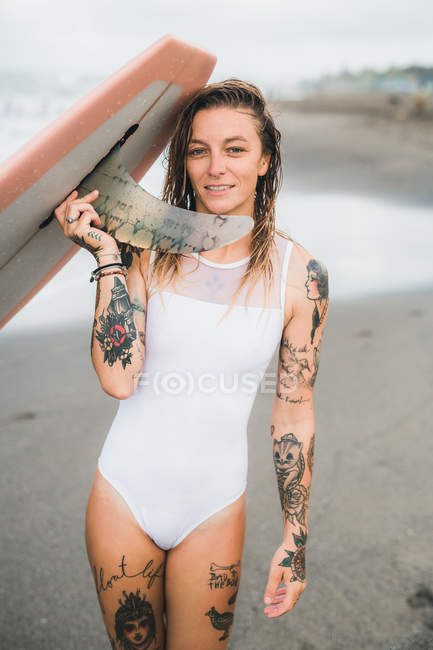 Женщина держит доску для серфинга на пляже — стоковое фото