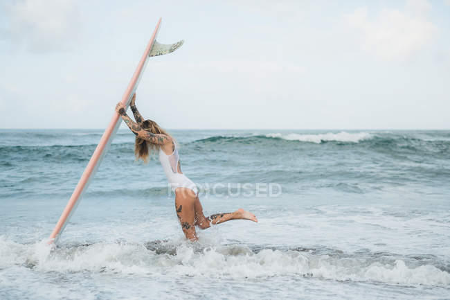 Mujer sosteniendo tabla de surf en la playa - foto de stock