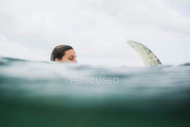 Woman in sea water with surf board — Stock Photo