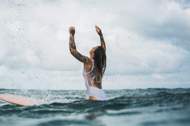 Femme assise sur une planche de surf — Photo de stock
