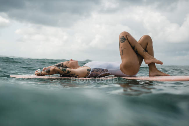 Жінка лежить на дошці для серфінгу — стокове фото