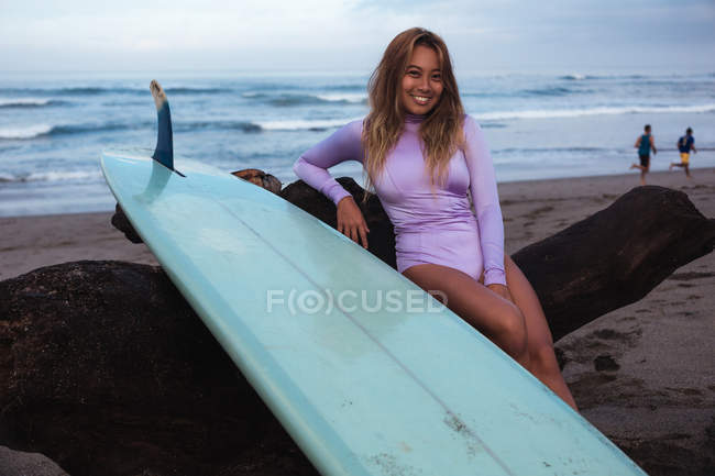 Surfer sitting with surf board on beach — Stock Photo