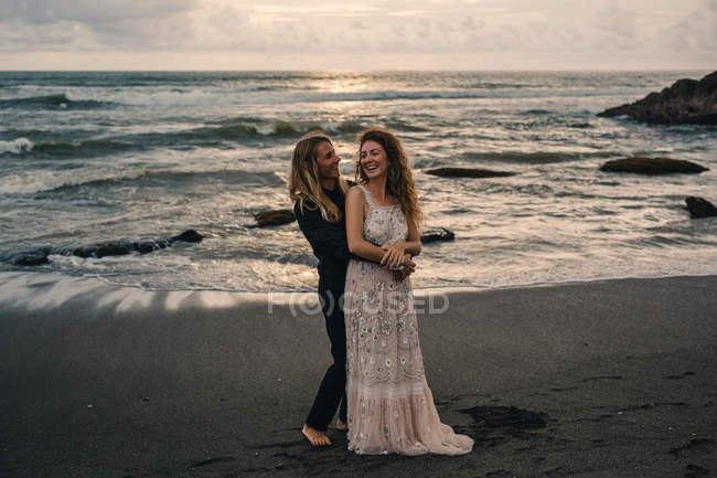 Vista frontal do homem abraçando a mulher na praia de areia — Fotografia de Stock