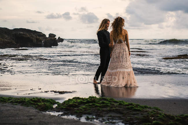 Вид сзади чувственной пары, наслаждающейся временем на отдаленном пляже на закате — стоковое фото