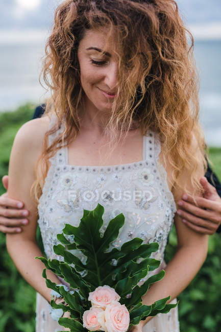 Front view of woman holding flowers with man hugging her — Stock Photo