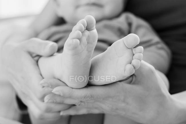 Pieds d'enfant dans les mains de la mère — Photo de stock