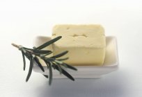 Closeup view of fresh butter in a white dish with rosemary — Stock Photo