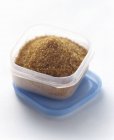 Closeup view of brown sugar crystals in plastic storage container — Stock Photo