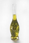 Vue rapprochée de l'huile infusée d'herbes dans une bouteille en verre — Photo de stock