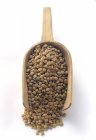 Closeup view of green lentils in wooden shovel on white surface — Stock Photo