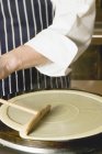 Cropped view of a person frying a crepe on a crepe iron — Stock Photo