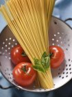 Bunch of dried spaghetti and tomatoes — Stock Photo