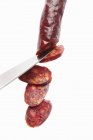 Faca lâmina de corte Chorizo salsicha no fundo branco — Fotografia de Stock