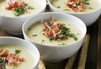 Celery soup with bacon and parsley in white bowls — Stock Photo