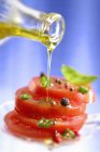 Tomates picados sendo regados com azeite no fundo azul — Fotografia de Stock
