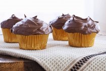 Chocolate cupcakes on tablecloth — Stock Photo