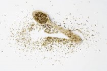 Top view of dried oregano on a spoon and on a white surface — Stock Photo