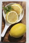 Fresh lemon with halves in dish — Stock Photo