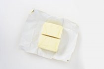 Top view of a halved pat of butter on paper — Stock Photo
