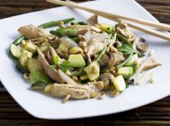 Chicken fillet with avocado, courgette, shallots and pine nuts  on white plate with wooden sticks — Stock Photo
