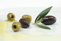 Schwarze und grüne Oliven mit Blättern — Stockfoto