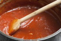 Горщик простий томатному соусі і дерев'яною ложкою — стокове фото