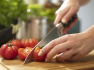 Жіночі руки нарізають помідори — стокове фото