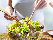 Primo piano vista ritagliata della donna mescolando insalata in ciotola — Foto stock