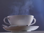 Nahaufnahme einer dampfenden Tasse Suppe mit Löffel auf Teller — Stockfoto