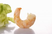 Closeup view of cooked prawn and lettuce leaf on white surface — Stock Photo