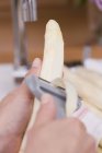Female hands peeling asparagus — Stock Photo