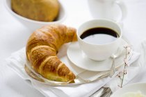 Cup of coffee and a croissant — Stock Photo