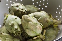Alcachofras de bebê em um coador — Fotografia de Stock