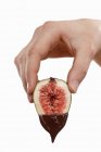 Hand holding fig dripping with chocolate — Stock Photo