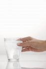 Cropped view of a hand holding a glass with an effervescent tablet — Stock Photo