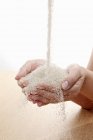 Closeup view of raw sugar flowing into hands — Stock Photo