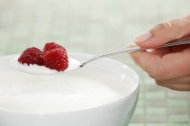 Hand holding spoon with yogurt — Stock Photo