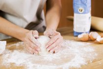 Femme préparant la pâte sur une surface farinée — Photo de stock