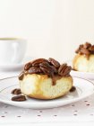 Sticky Pecan Date Bun - sweet bread roll with pecan nuts and dates on white plate — Stock Photo