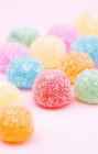 Vista de cerca de las bolas de goma de mascar en azúcar en la superficie de color rosa - foto de stock