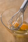 Whisk and egg yolk — Stock Photo