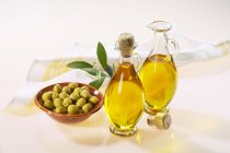 Olive oil in bottles and green olives — Stock Photo
