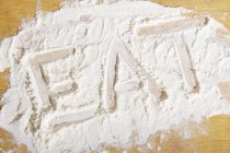 Word eat written in flour — Stock Photo