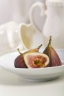 Half and whole figs in white bowl — Stock Photo